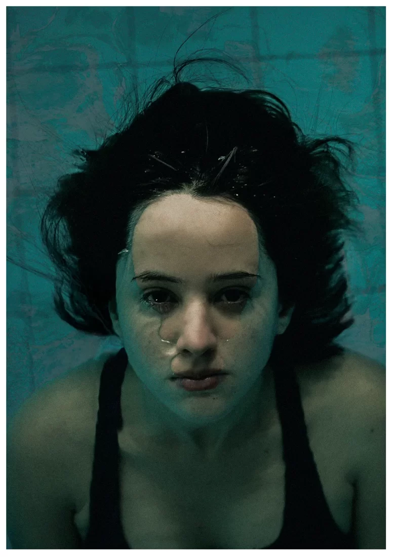 Foto de moça com o rosto semi submerso em uma piscina com filtro esverdeado