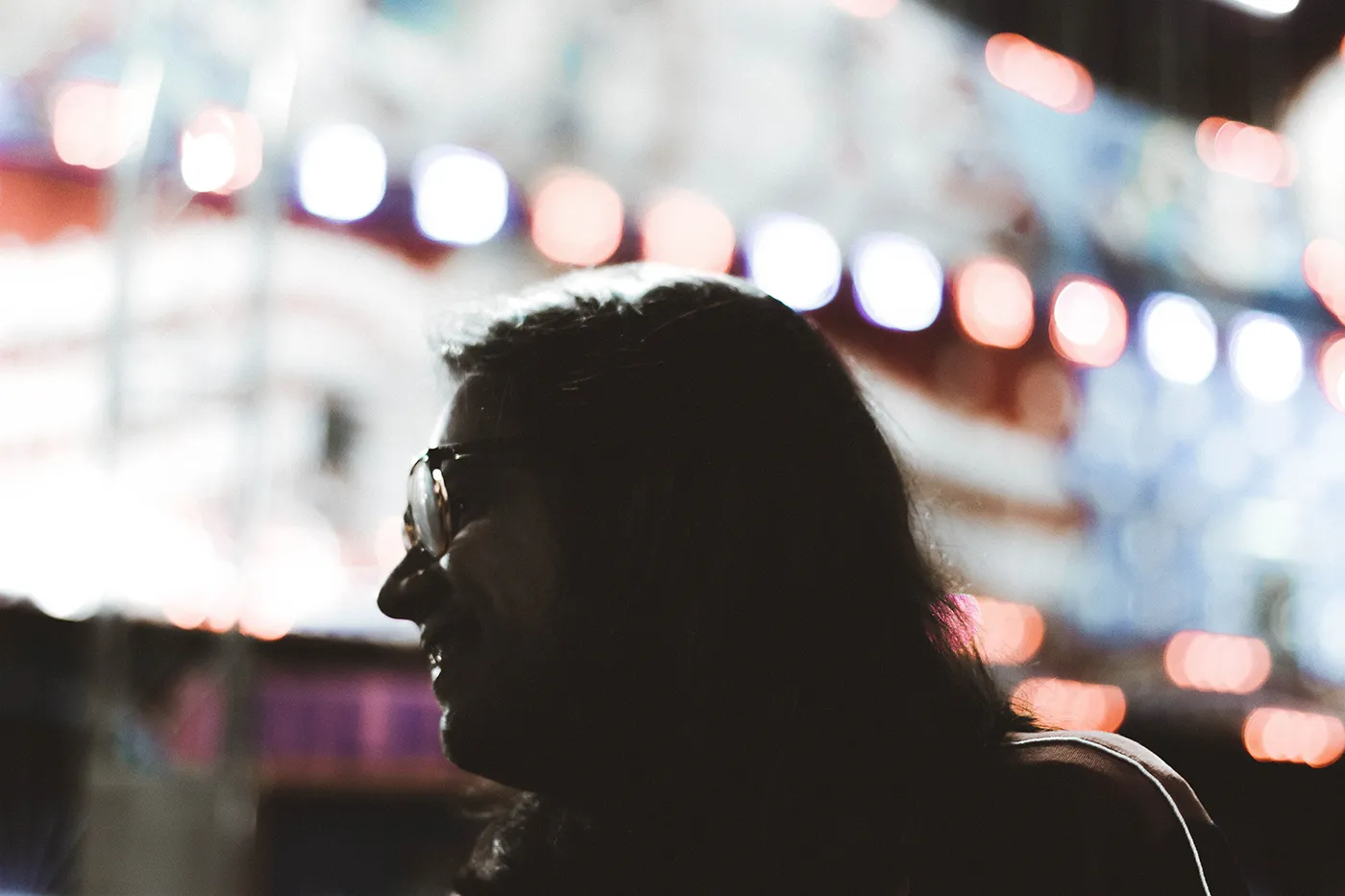 silhoute of a man with long hair and glasses at a theme park