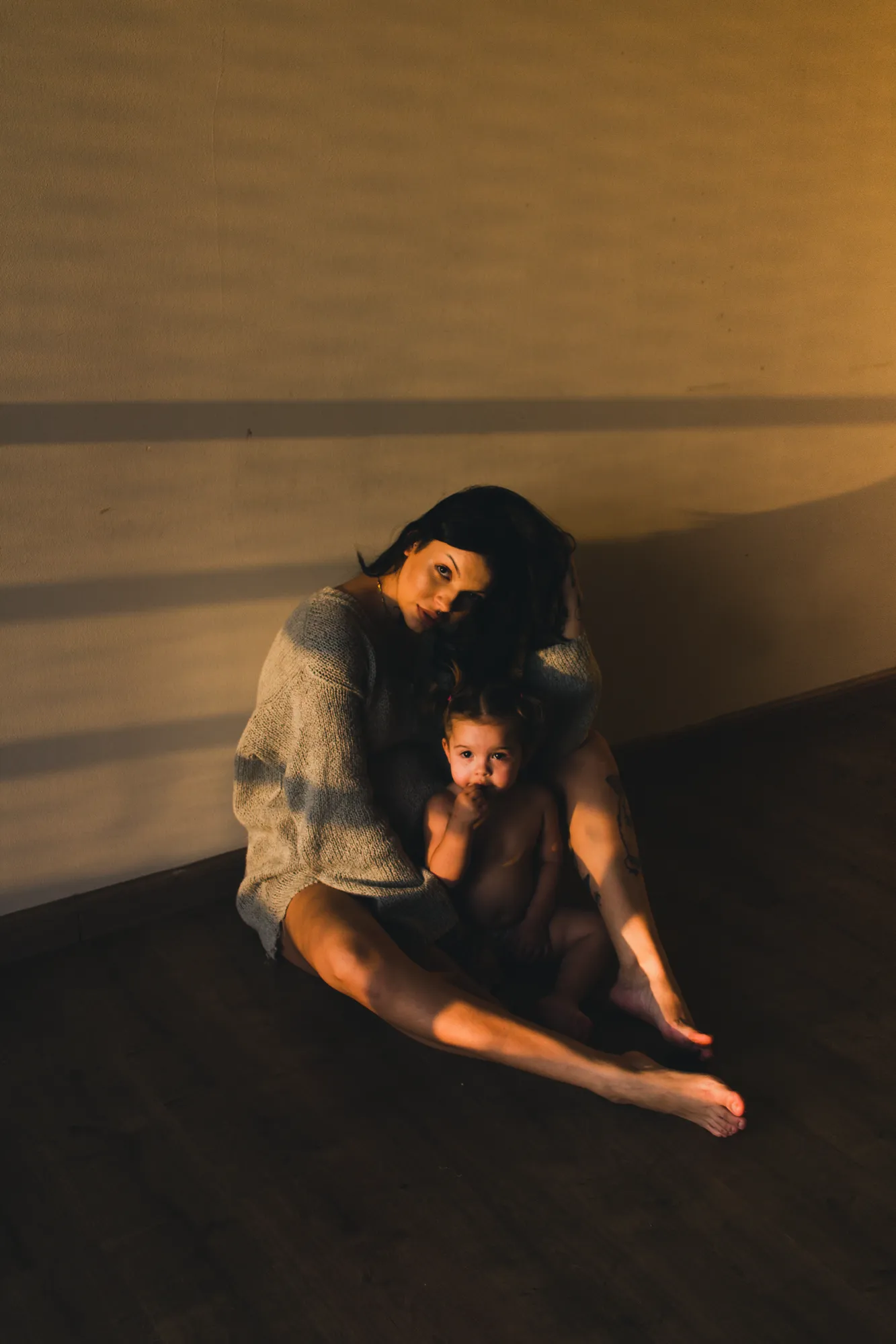 Mother and Child in Natural Light – Intimate Portraiture by Rodrigo Baumgratz Captured in black and white, this portrait explores the raw, quiet bond between a woman and child in a bare interior space. Rodrigo Baumgratz uses natural light and minimal composition to reveal vulnerability, strength, and emotional stillness—ideal for personal projects, editorial commissions, or campaigns exploring identity, motherhood, and domestic presence.