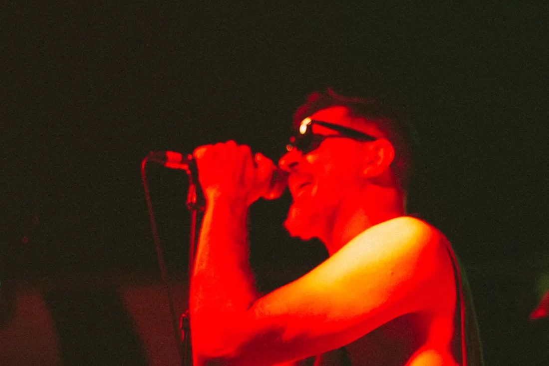 Man in red lighting singing with passion. A lot of grain