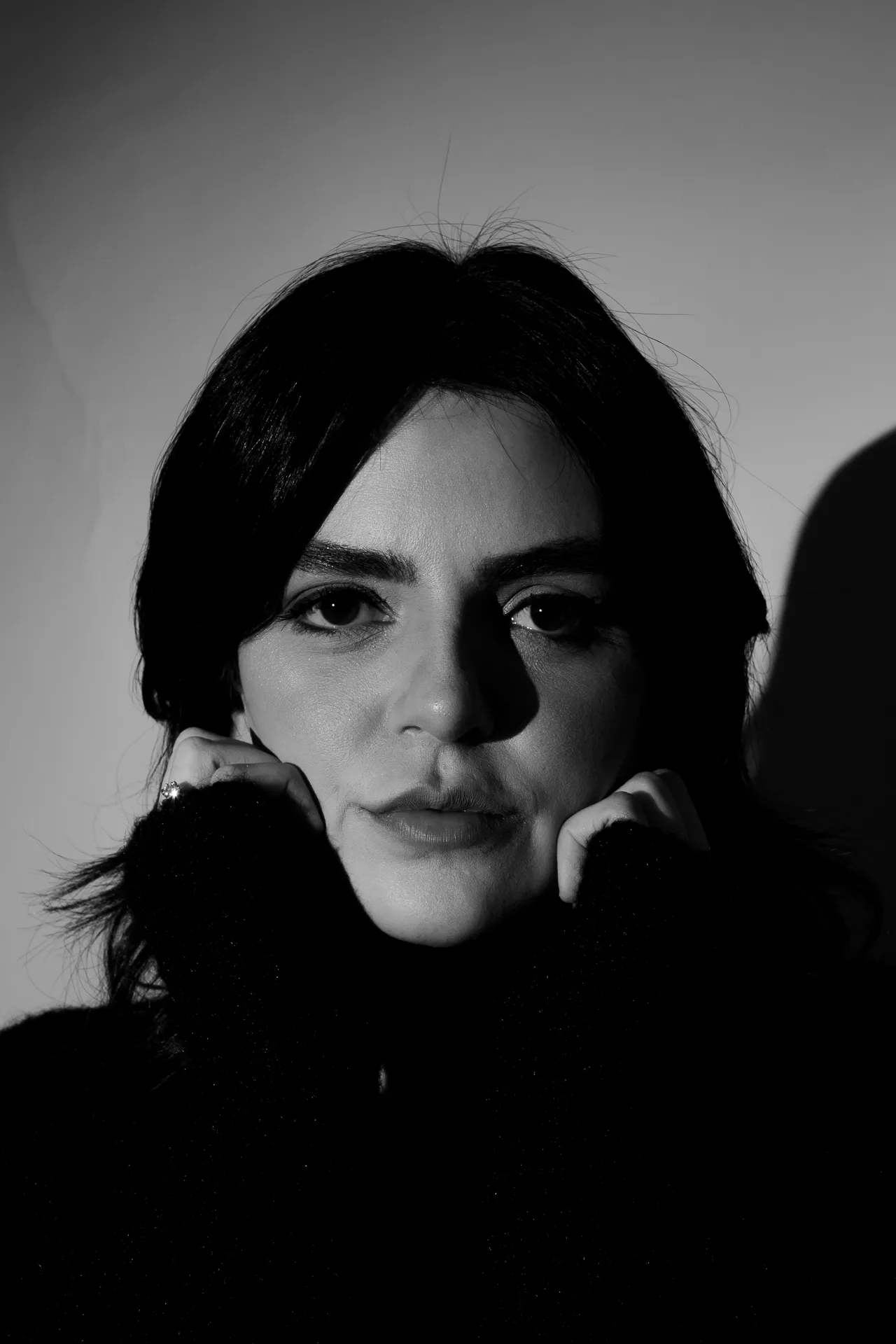 portrait of a woman with her hands holding her face. Shot on black and white