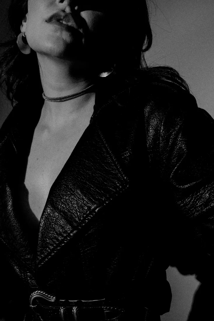 black and white photo of a woman cropped showing only her mouth and chest. she is wearing a leather jacket