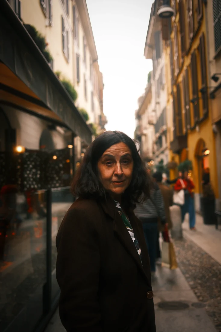 Candid Portrait in Urban Passage – Photography by Rodrigo Baumgratz Captured on a narrow street in Milan, this black and white portrait centers on a solitary figure amidst an active urban backdrop. Rodrigo Baumgratz balances emotional subtlety with compositional restraint, highlighting human presence within the flow of city life. Ideal for editorial portraits, documentary-style campaigns, or projects exploring identity in public space.