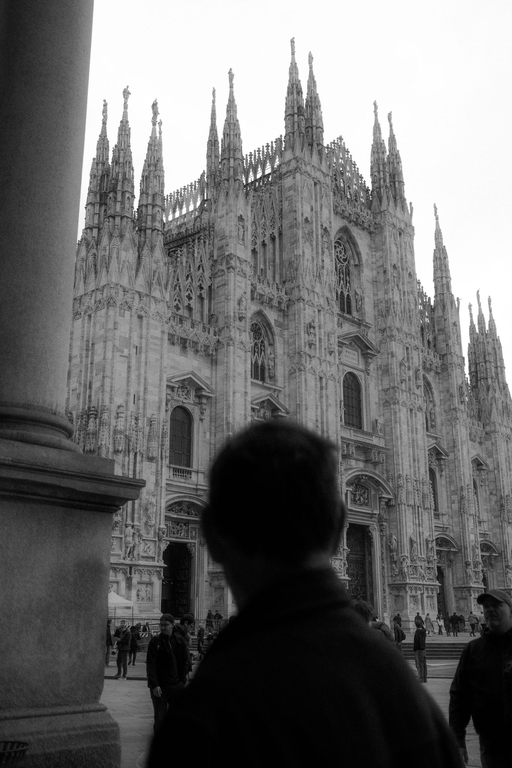 Human Perspective and Gothic Grandeur by Rodrigo Baumgratz In this evocative photograph by Rodrigo Baumgratz, the Duomo di Milano rises in its full Gothic splendor, framed against the blurred silhouette of a man observing the cathedral. The interplay of monumental stone architecture and the human presence creates a striking contrast between eternity and fleeting life. Ideal for portfolios that blend fine art travel photography, architectural storytelling, and a visceral exploration of urban spirituality. Perfect for searches on Milan cathedral photography, Gothic architecture photo art, and contemporary creative travel imagery.
