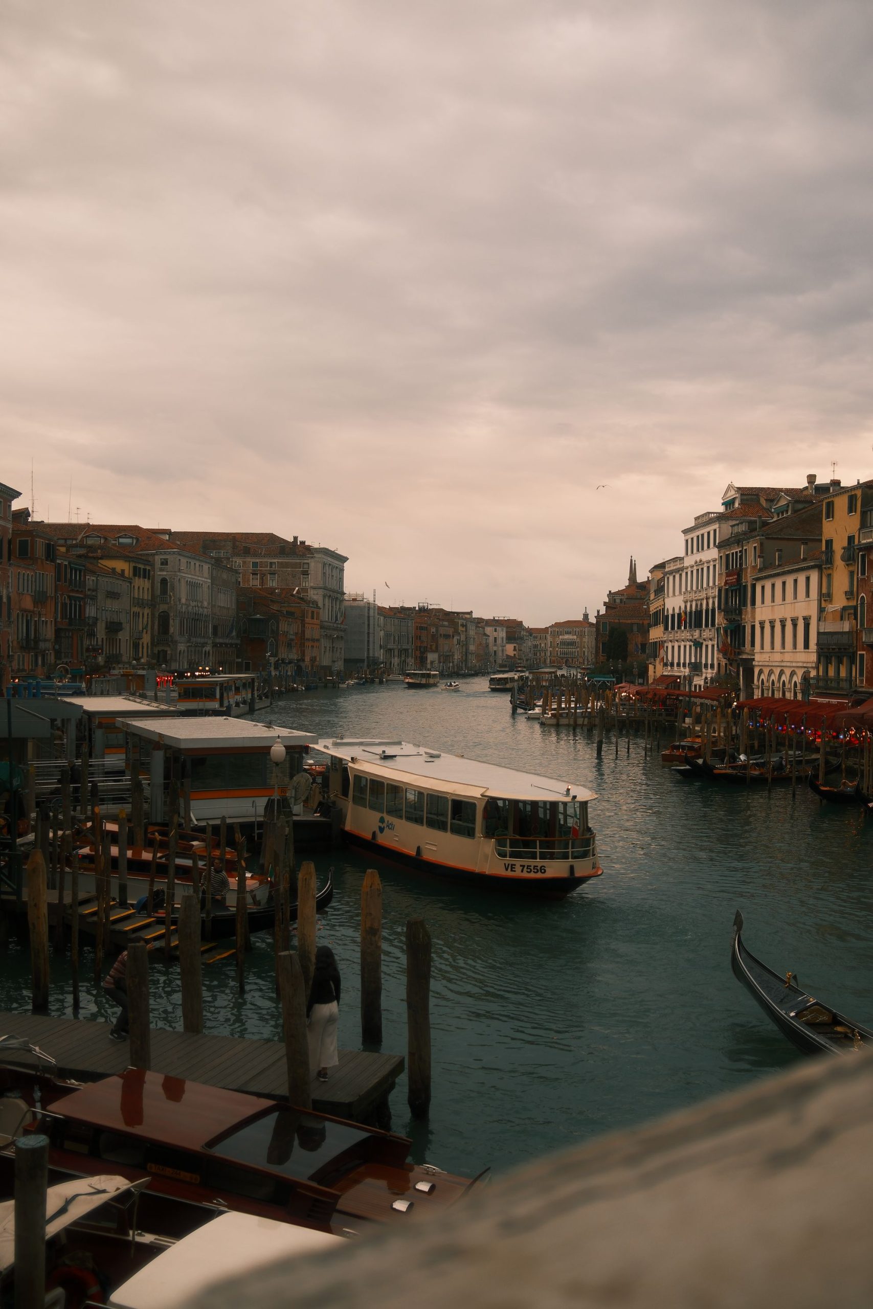 Venice Vaporetto on the Grand Canal – Atmospheric Travel Photography Rodrigo Baumgratz captures Venice’s lifeline, the Grand Canal, under a cloudy sky, where the vaporetto navigates among gondolas and moored boats. The muted light and dense architecture lining the water evoke both the everyday rhythm of Venetian life and its timeless cinematic aura.
