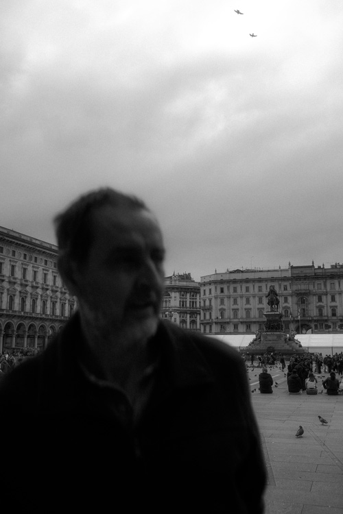 Blurry Identity in Piazza del Duomo – Conceptual Urban Photography by Rodrigo Baumgratz. Shot in Milan's iconic Piazza del Duomo, this conceptual black and white photograph explores themes of anonymity and memory through a blurred foreground subject set against sharp architectural detail and historical monuments. The image draws attention to human presence as both fleeting and integral to the urban experience. Ideal for editorial projects, album covers, or campaigns that seek poetic ambiguity, narrative tension, and artistic direction rooted in emotion and space.