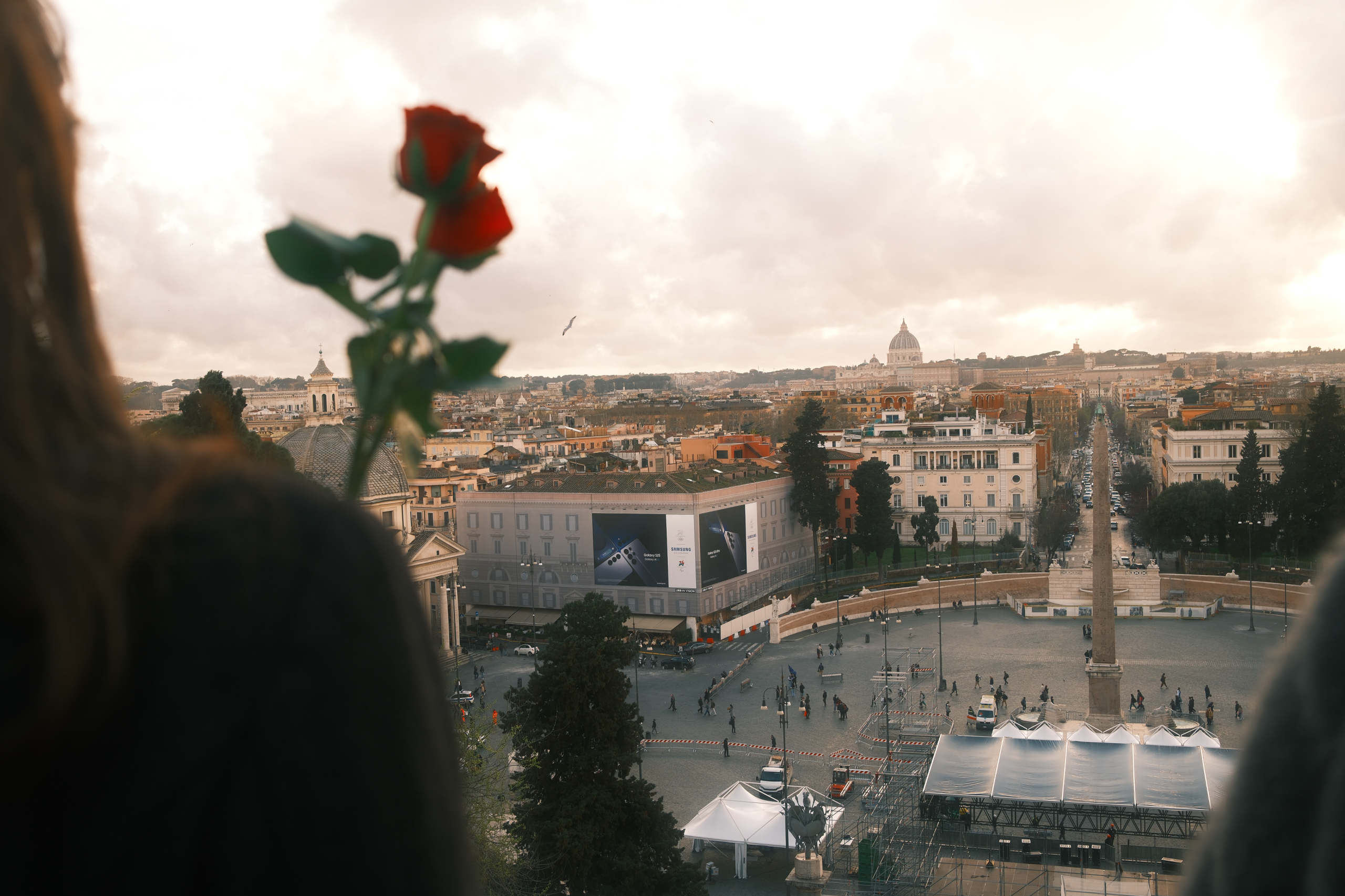 City View with Gesture – Narrative Urban Photography in Rome by Rodrigo Baumgratz
Overlooking Piazza del Popolo with a distant view of St. Peter’s Basilica, this image introduces a human presence through a symbolic gesture: a hand offering a rose in the foreground. Rodrigo Baumgratz merges compositional structure with emotional detail, crafting a photograph that bridges cityscape with story—ideal for editorial projects, cultural campaigns, or visual essays on memory, space, and gesture.  